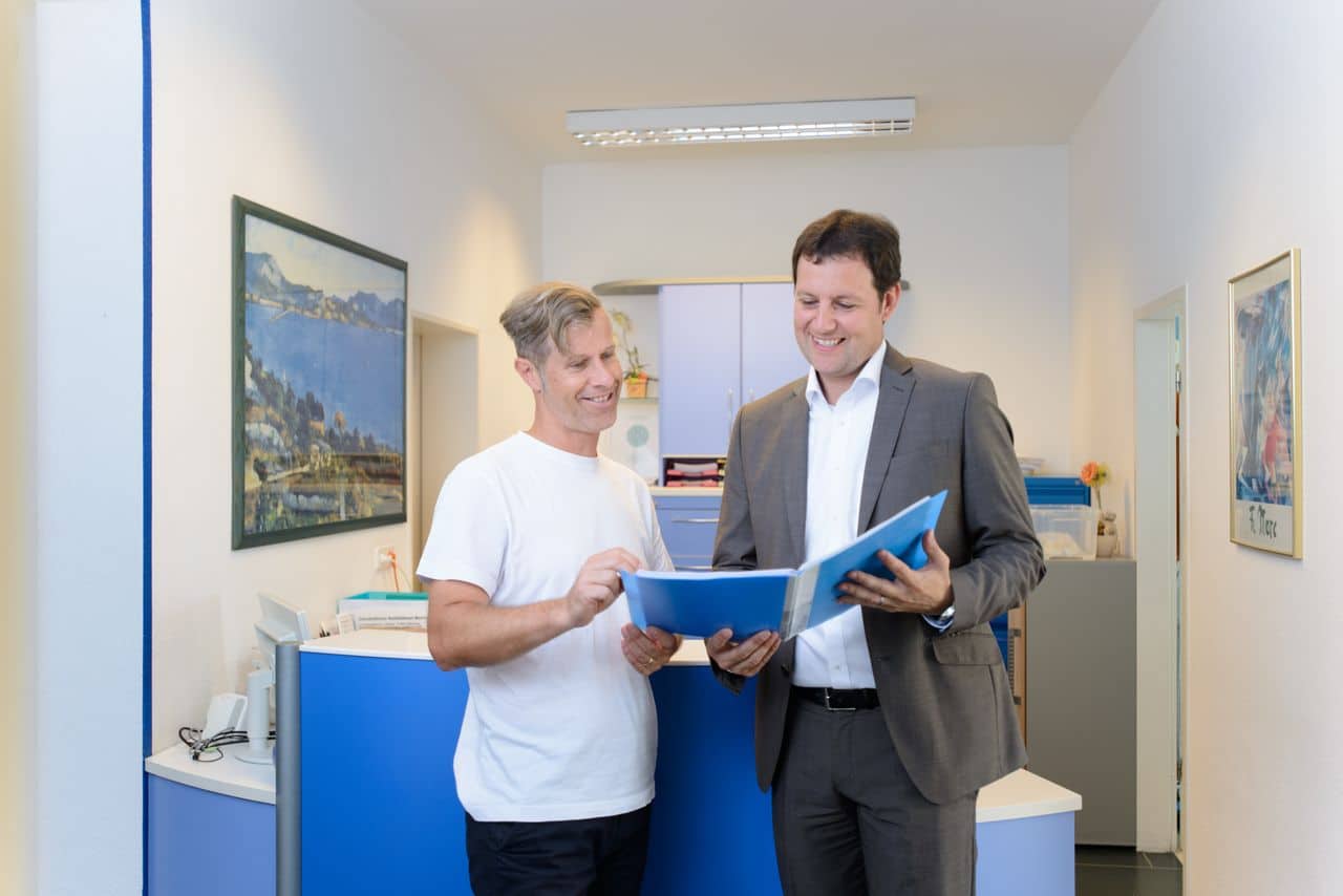 Steuerberatung für Heilberufe Fachberater für Gesundheitswesen (DStV e.V.) Michael Radtke und Dr. Egon Stein, Zahnarzt, besprechen in der Zahnarztpraxis eine Auswertung